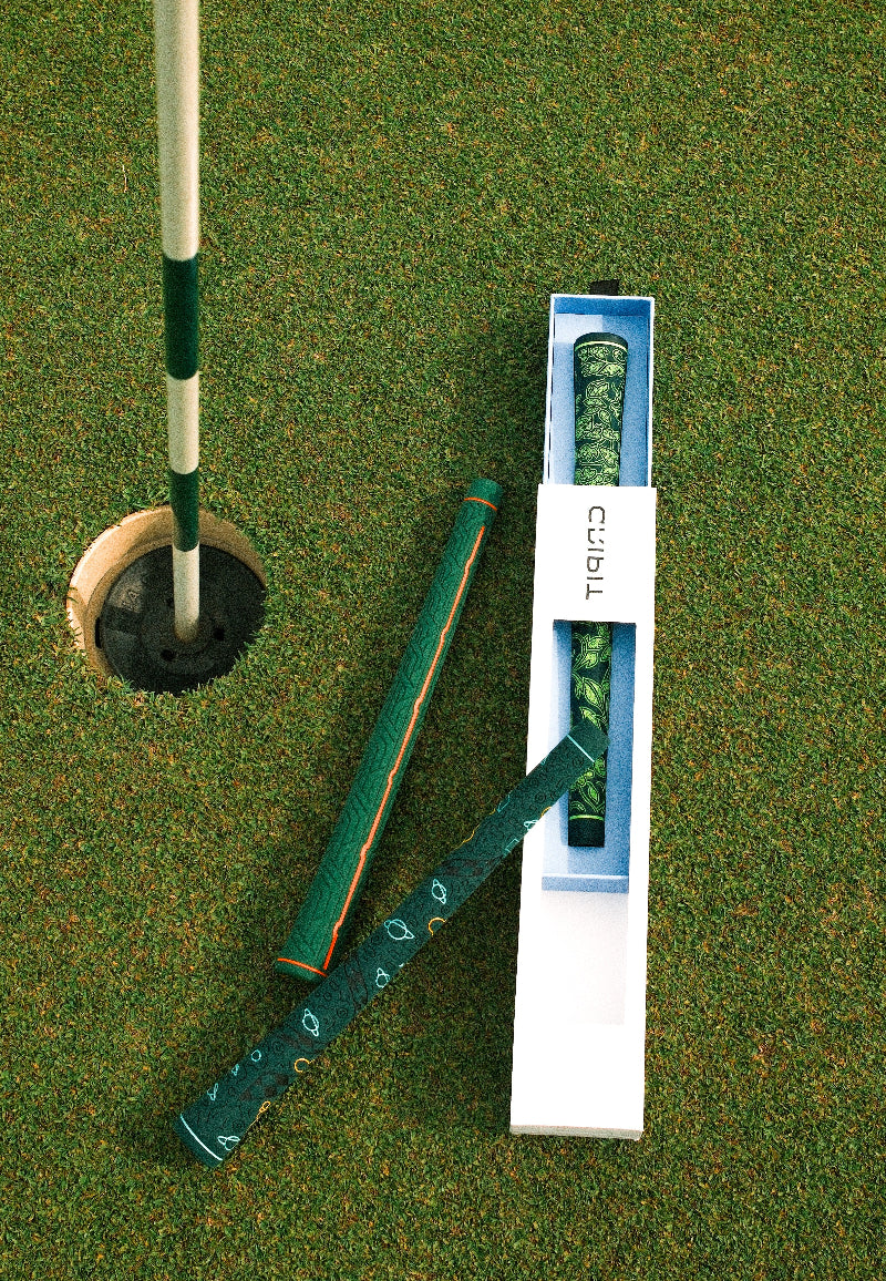 Golf putter and dollar-themed headcover beside a hole on the green.